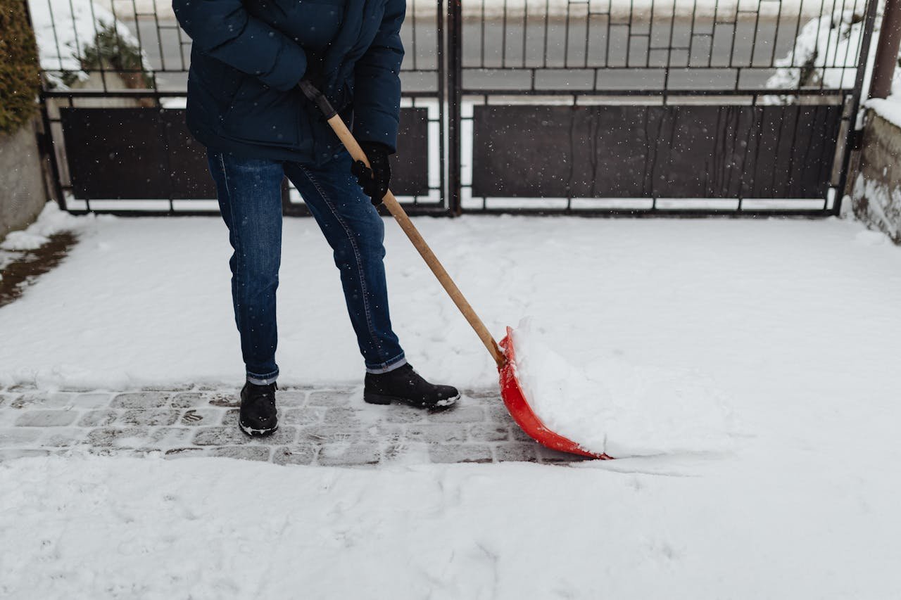 Crafting Captivating Headlines: Your awesome post title goes here A person shoveling snow on a paved path during a winter day, wearing warm clothing.
